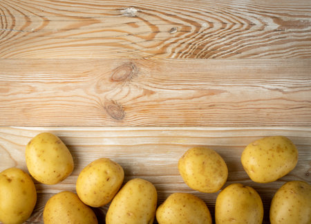 Raw whole potato pile on wooden background top view. Yellow washed potatoes mockup on vintage board texture pattern with copy space