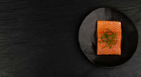 Slice of Raw Salmon Fillet on Black Background Mockup Top View. Thick Piece of Fresh Red Fish or Trout with Copy Spaceの写真素材