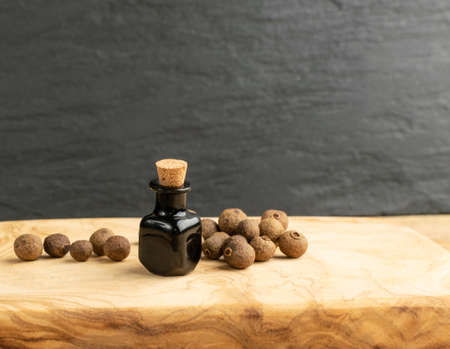 Allspice pepper seeds essential oil in small vintage bottle. Jamaica peppercorns and organic essential oil in medicine jar. Myrtle pepper essence, tincture, extract or infusion mockupの写真素材