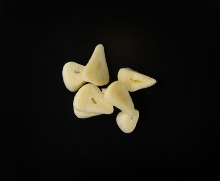 Fresh sliced garlic isolated on black background closeup. Macro shot of chopped crushed garlic cloves, cut into pieces food ingredientの写真素材