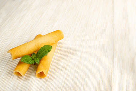 Crunchy Wafer Sticks on Light Beige Tablecloth Background. Crispy Biscuit Rolls, Sweet Sugar Bakeryの写真素材