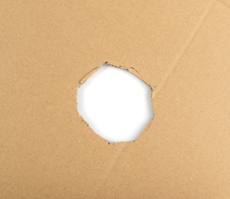 Cardboard hole background. Carton torn with copy space, craft paper frame top view