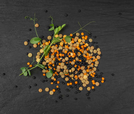 Brown, orange, black lentils and dry yellow peas. Legumes grains mix, dal, raw daal, dhal, masoor collection on black stone backgroundの写真素材