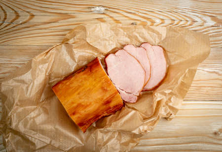 Smoked pork tenderloin, sliced ham, meat fillet on wooden table background top viewの写真素材