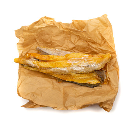 Dried fish sticks on crumpled craft paper. Dry salted seafood snack, hake stockfish, small pieces of...