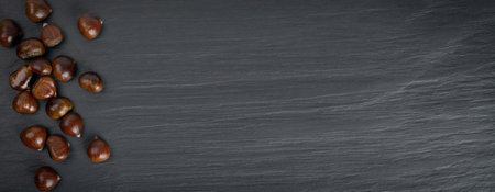 Edible sweet whole chestnuts pattern on black stone background with copy space top view. Set of raw healthy delicious chestnut, autumn and christmas veggie foodの写真素材