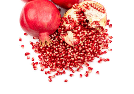 Scattered pomegranate seeds isolated on white background. Red punica granatum juicy grains top view