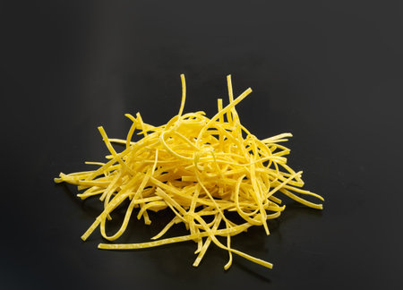 Raw yellow italian tagliatelle pasta. Egg homemade dry ribbon noodles, thin macaroni ribbons, short...