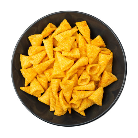 Corn cone pile on black plate isolated. Bugles chips, puffs with spices, crunchy puffed snacks,...