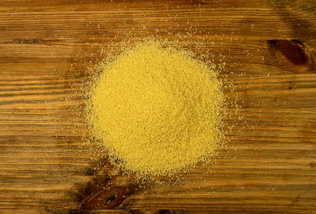 Couscous pile top view. Dry cuscus, raw kuskus, uncooked cous cous or semolina granules on wooden backgroundの写真素材