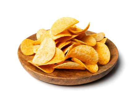 Potato chips pile on wood plate isolated. Crispy thin potato snack heap, fast food snacks with...