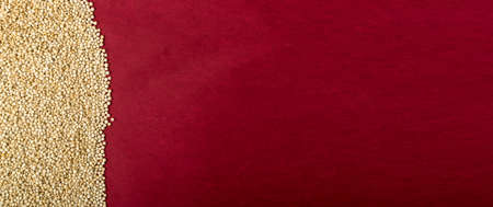 Quinoa Seeds on Red Background with Copy Space. Dry Organic Chenopodium Quinoa, Kinwa or Kinuwa Grains Purple Texture Pattern Top Viewの写真素材