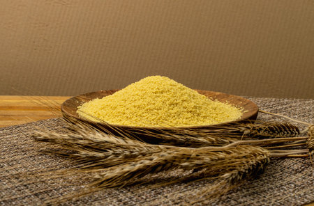 Couscous pile on wood plate side view. Dry cuscus, raw kuskus, uncooked cous cous or semolina...