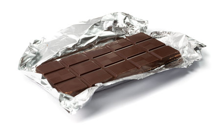 Chocolate bar on silver foil isolated. A whole chocolate blok with square segments in foil packaging...