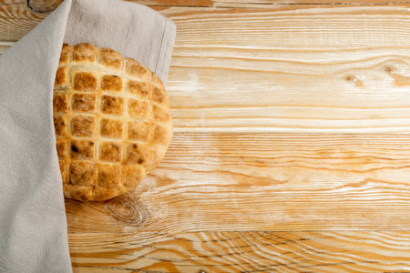 Focaccia bread on wood table. Homemade round ciabatta, rustic thick flatbread, traditional wheat loaf bun, circle flat breadの写真素材
