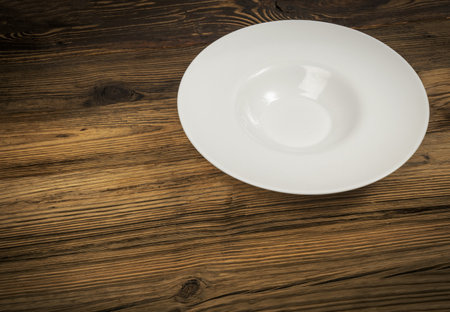 Empty white pasta plate on wooden table background with copy space. rustic kitchen mockupの写真素材
