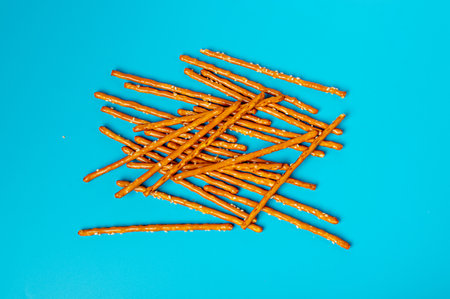 Bread Sticks, Pretzel Straws, Sesame Grissini, Pretzels Snack with Sesame Seeds, Long Rusks on Blue Background Top Viewの写真素材