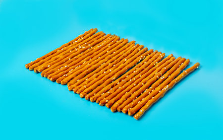 Bread Sticks, Pretzel Straws, Sesame Grissini, Pretzels Snack with Sesame Seeds, Long Rusks on Blue...