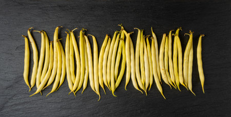 Yellow French Beans on Black Plate, Raw String Beans Pile, Fresh Wax Bean Pods on Dark Stone Backgroundの写真素材