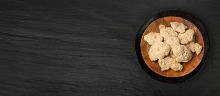 Raw Dehydrated Soy Meat on Black Plate Background, Soya Chunks Top View Mockup, Texturized Vegetable Protein, also known as TSP on Round Wood Plate, Copy Spaceの写真素材