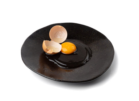 One Broken Egg in Black Bowl, Raw Yolk and White, Fresh Broken Organic Chicken Egg on Wooden Rustic...