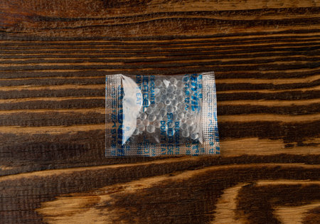 Desiccant Silica Gel Adsorbent Sachet, Desiccant Polymer Bag, Silicagel Bags on Wood Background Top Viewの写真素材