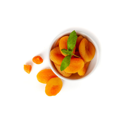 Dry Apricot Stack with Green Leaves Isolated, Dried Apricots Pile in Bowl, Healthy Orange Fruits Group, Sweet Organic Dessert Snack, Healthy Diet Food, Dry Apricots on White Backgroundの写真素材
