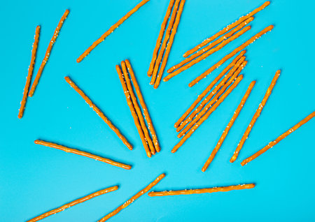 Bread Sticks, Pretzel Straws, Sesame Grissini, Pretzels Snack with Sesame Seeds, Long Rusks on Blue Background Top Viewの写真素材