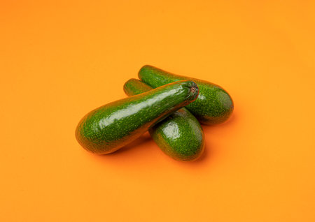 Avocado Isolated, Whole Avokado Set, Three Green Avocados Pile, Fresh Alligator Pear, Guacamole Ingredient, Long Avocado Fruit on Orange Backgroundの写真素材