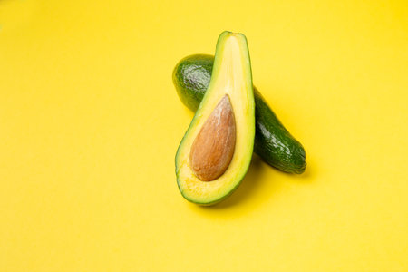 Avocado Isolated, Whole Avokado, Green Avocados Slice, Fresh Alligator Pear, Guacamole Ingredient, Long Avocado Fruit on Yellow Backgroundの写真素材
