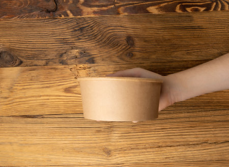 Bowl in Hands, Empty Bowl in Arms on Wooden Background, Vintage Kitchen Tableware Mockup, Dishware Banner, Empty Plate, Starving, Hungry Concept, Paper Bowl with Copy Space for Textの写真素材