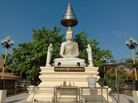 Buddha statue white sitting on Buddha altar with umbrella cover isolated on blue sky background closeup.のeditorial素材
