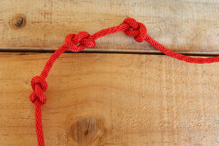 Red ship ropes tied knot on wooden background closeup.の写真素材