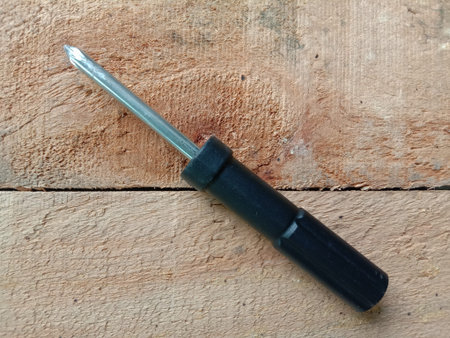 Screwdriver black handle, top view isolated on wooden flooring background closeup.