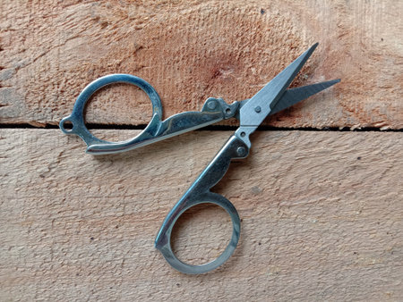 Small scissors metal, top view isolated on wooden flooring background closeup.