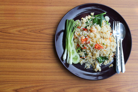 Fried rice on black dish with spoons and forks delicious food for Thai people isolated on wooden...