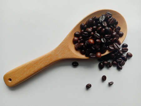 Coffee seeds in wooden spoon isolated on white background closeup.の写真素材