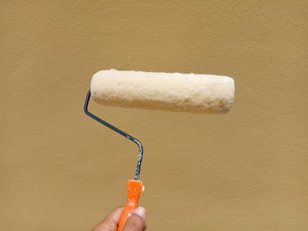 Painter is painting with the paint roller on cement wall closeup.の写真素材