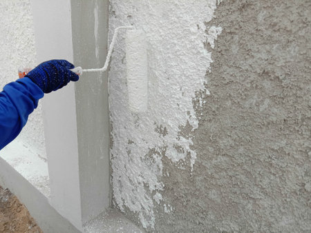 Painter is painting with the paint roller on cement wall closeup.の写真素材