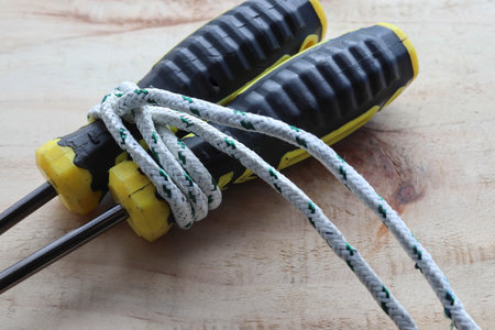 Ship ropes tied with screwdriver handle isolated on wooden background closeup.