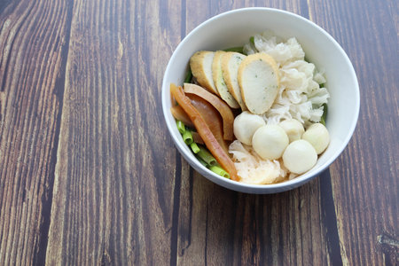 Yentafo noodles with fishes ball in white bowl, Thai delicious food isolated on wooden wallpaper background closeup.の写真素材