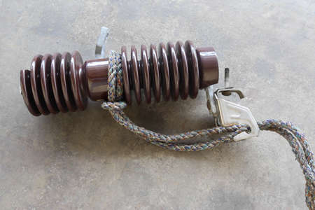 Ship ropes tied to knot, old porcelain electrical insulator isolated on cement flooring background closeup.の写真素材