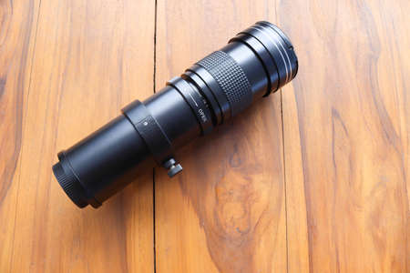 Super telephoto lens zoom, for photographer isolated on wooden background closeup.の写真素材