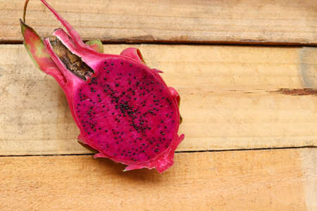 Dragon fruit half slice with copy space isolated on wooden background closeup.の写真素材