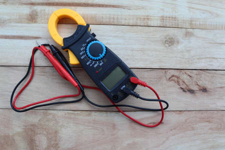 Digital clamp-on meter with probes, electrical measuring instruments isolated on wooden background closeup.の写真素材