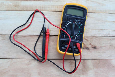 Digital multimeter with probes, electrical measuring instruments isolated on wooden background closeup.の写真素材