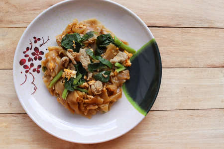 Stir-fried rice noodles, soy sauce with pork and kale in the dish, Thai delicious food isolated on wooden background closeup.の写真素材