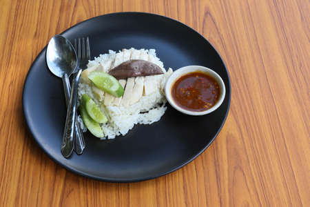 Chicken rice, top view with spoon and fork in the black dish isolated on wooden background closeup.の写真素材
