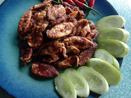 Fried squid with chili and sliced cucumber on blue plate.