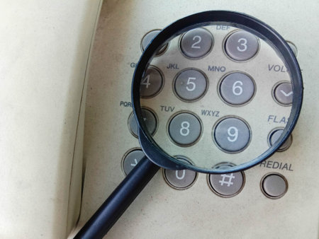 Old phone and magnifying glass on the table. Vintage style.